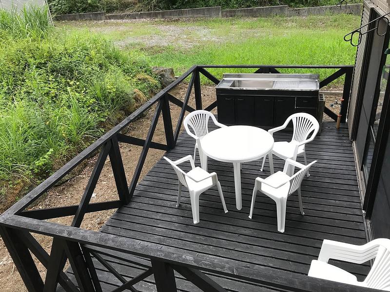 緑に囲まれた屋外のバーベキューエリアとテーブルセット